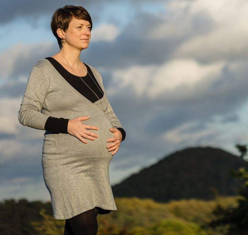 Photo de la Doula r'Eve enceinte tenant son ventre et qui regarde le soleil