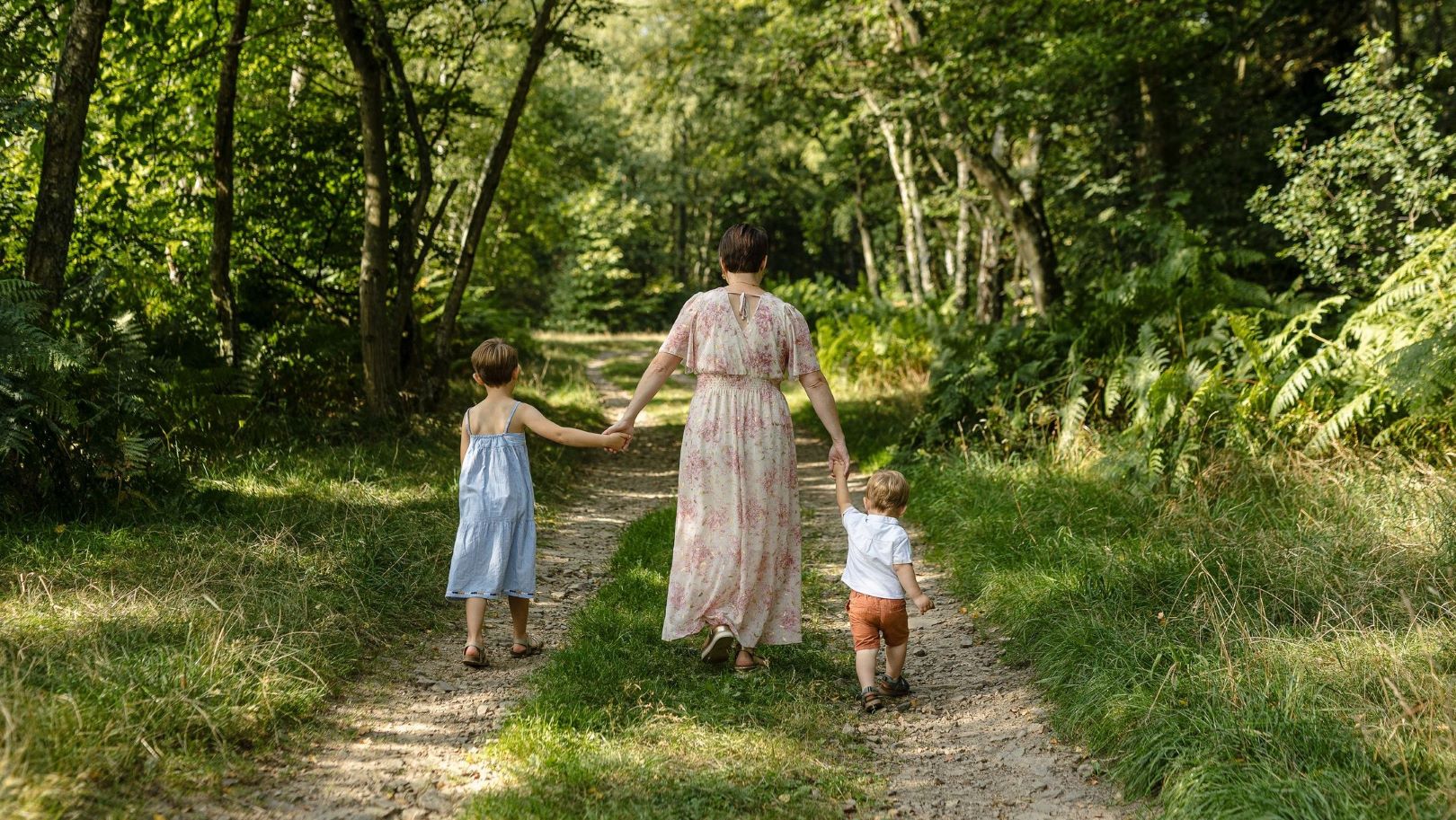 Photo de la doula r'Eve dans les bois tenant ses enfants par la main