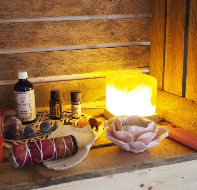 Photo d'une étagère en bois avec des huiles essentielles, des pierres et un bâton de fumigation