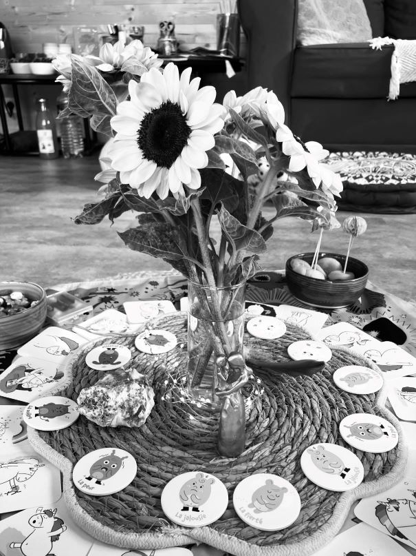 Photo noir et blanc d'une décoration avec une fleur et des cartes pour enfant lors d'un cercle parent/enfant organisé par la doula r'Eve
